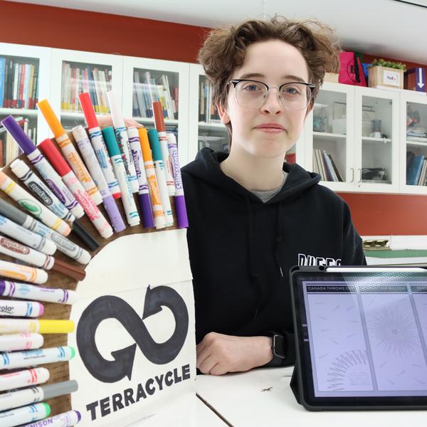 Emma sits next to a display of pens.
