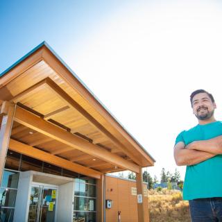 Hayden stands in front of Shq'apthut, VIU's Indigenous gathering place on the Nanaimo campus