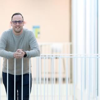 Dr. Kyle Duncan, a VIU Chemistry Professor,  smiles while leaning against a white railing.