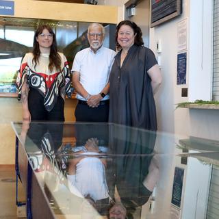 Three people pose with a tank