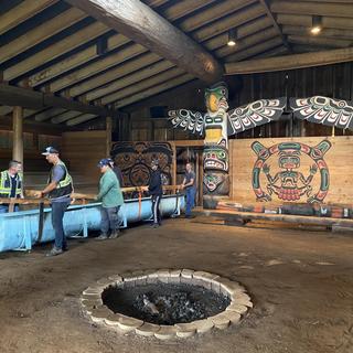 K’ómoks First Nation Guardians, Archaeologists, Royal BC Museum and Coastal Transportation Solutions collaborators move the panel out of the KFN Big House to its new temporary home at the VIU Deep Bay Marine Field Station. 