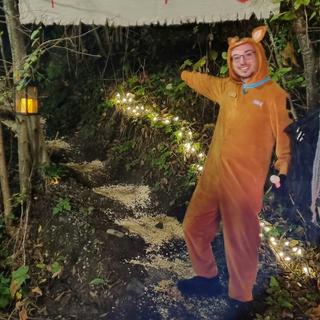 A man in a brown rabbit costume points up a trail