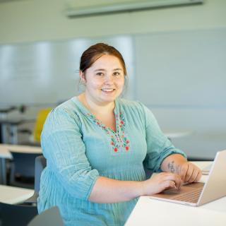 Sarah types on a laptop in a classroom