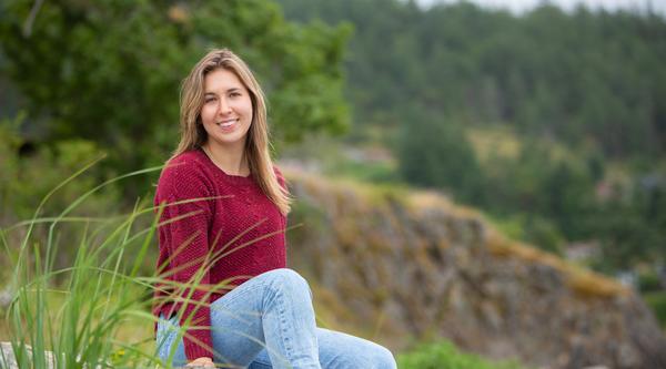 Portrait of Marissa sitting on grass smiling at camera