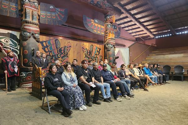 A group of students sits in a longhouse