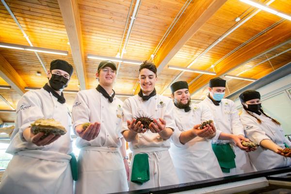 Culinary arts students hold different seafood items