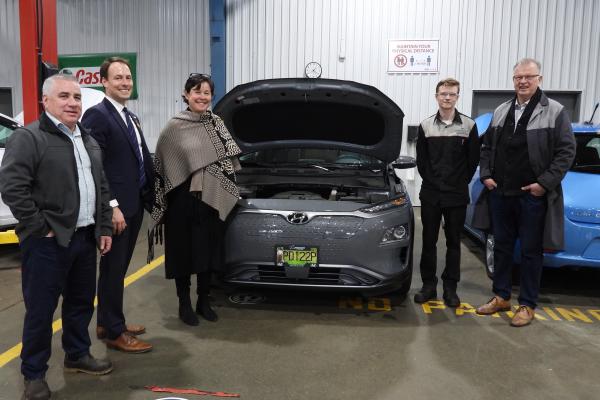 Five people pose around an electric vehicle