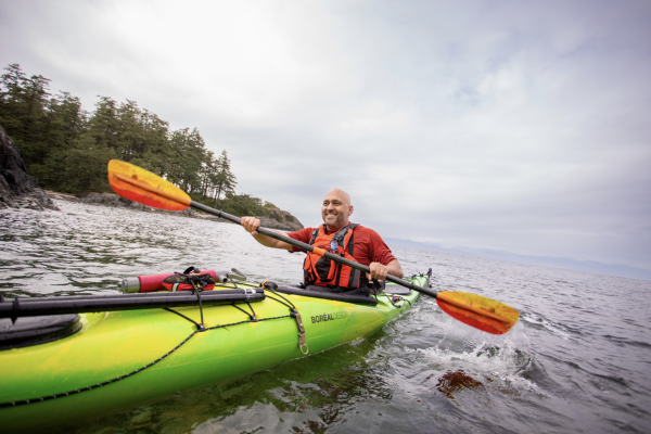 Farhad Moghimefar paddling a kayak and smiling off into the distance