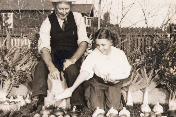 A man and a woman kneel behind produce laid out on grass