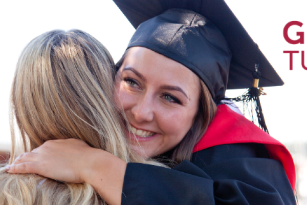 Student in grad cap hugs someone with words Giving Tuesday on side