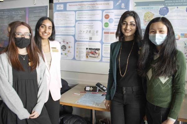 Four students standing in front of a poster