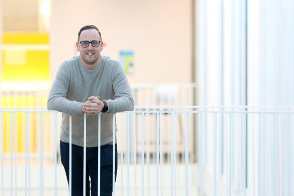 Dr. Kyle Duncan, a VIU Chemistry Professor,  smiles while leaning against a white railing.