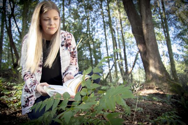 Mandy Hobkirk uses an identification book while examining plants at VIU's Nanaimo Campus.