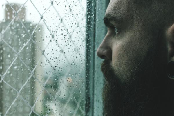 Man staring out the window at the rain