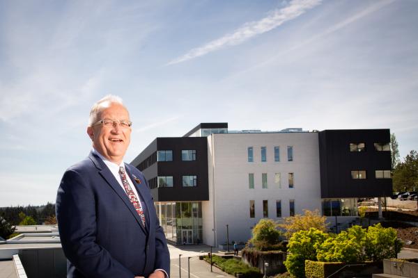 Ralph Nilson, former VIU president, smiles with the Dr. Ralph Nilson Centre for Health and Science in the background