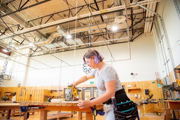 Female cutting a board in carpentry shop