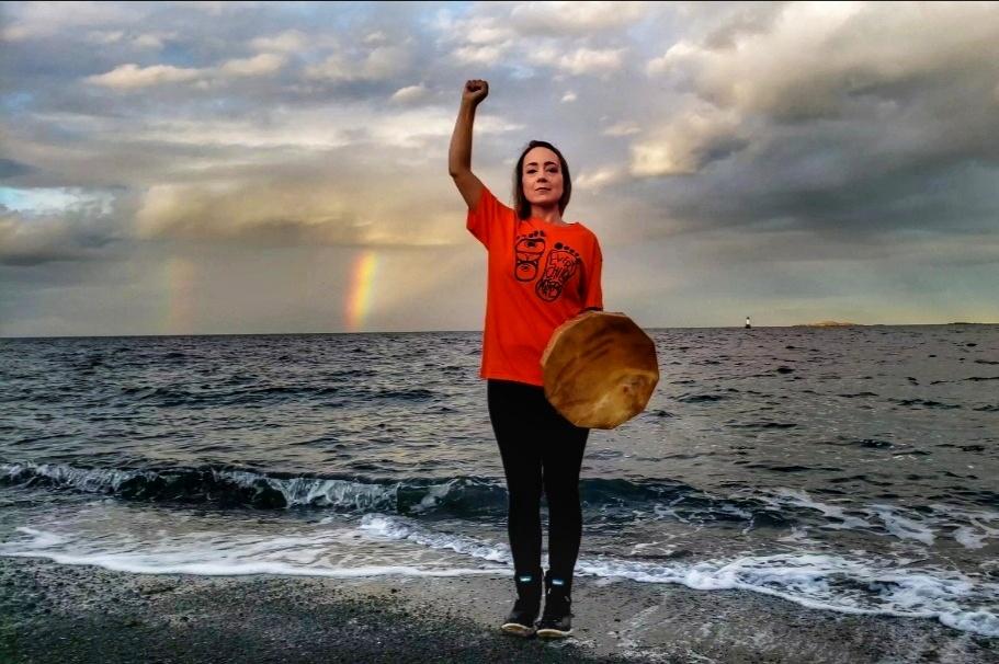 Falon Crosby near ocean holding a drum