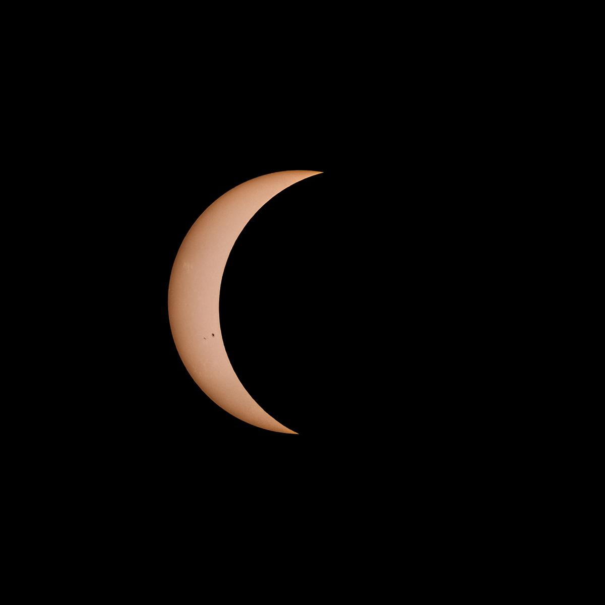 Just a sliver of sun is visible behind the moon.