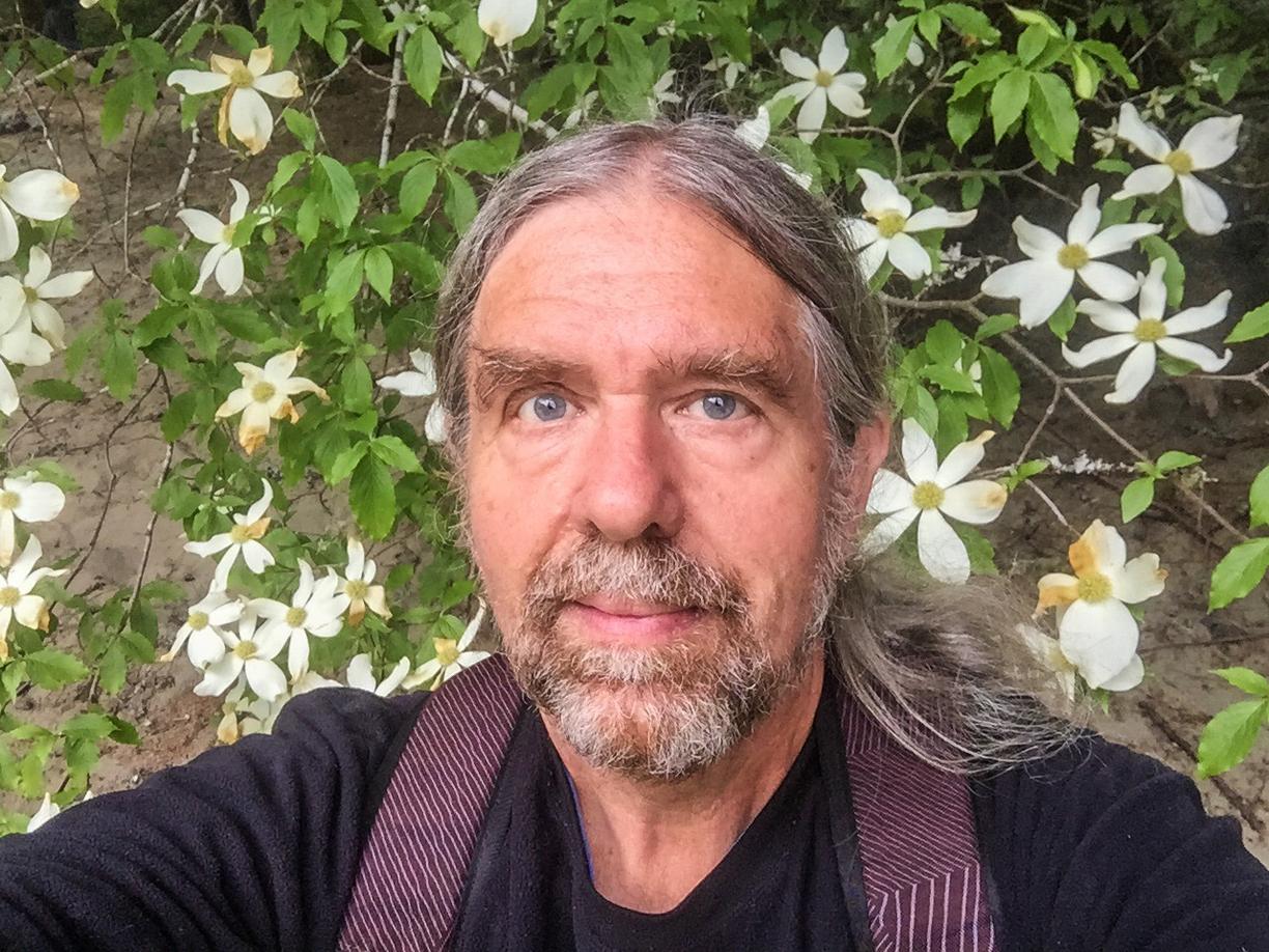 Craig Evans standing in front of some white flowers