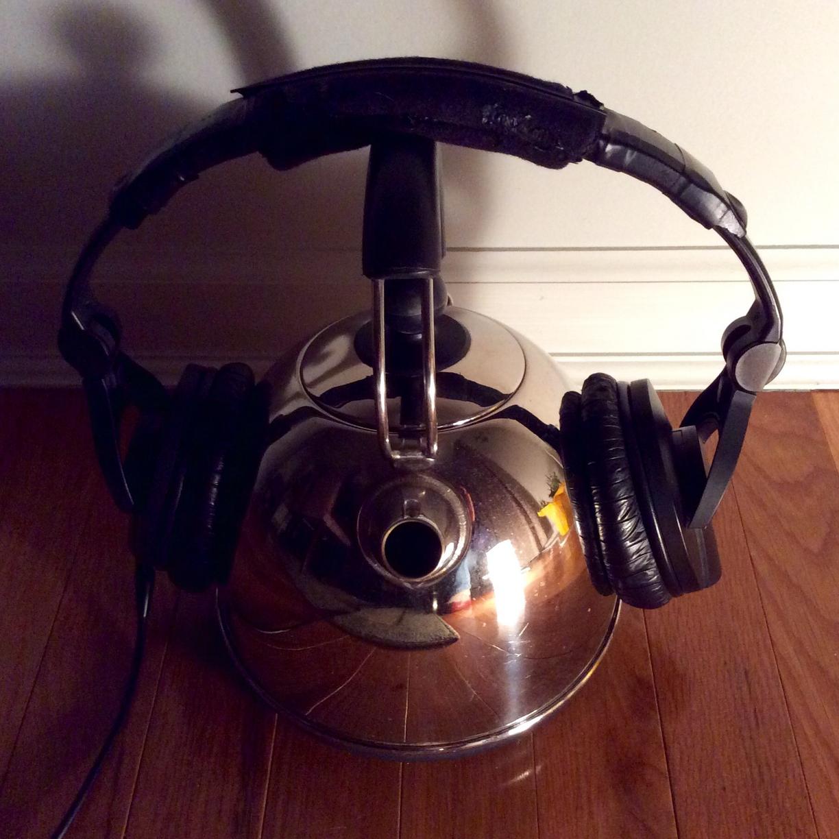 Headphones resting on a tea kettle.