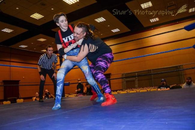 Meara Kimball puts Kyle V in a headlock during a wrestling practice in a ring