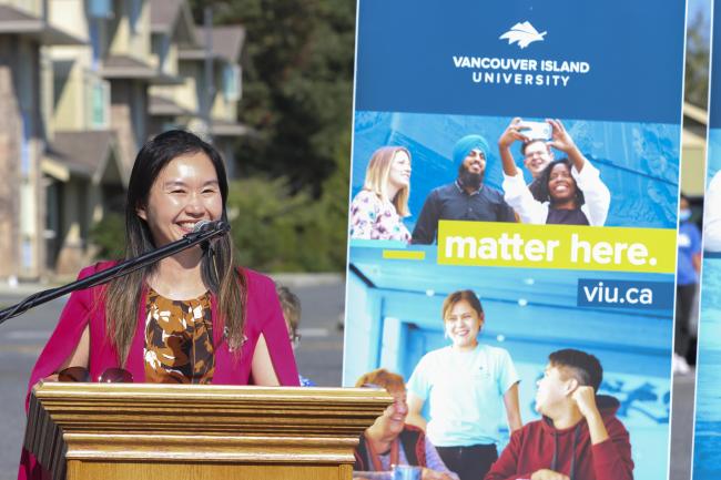 Former Advanced Education and Skills Training Minister Anne Kang speaks at a podium 