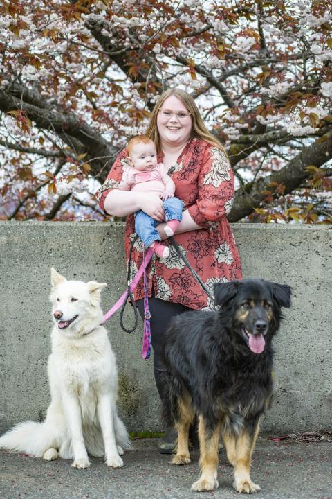 Amy with a baby in her arms and her two dogs