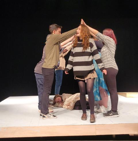 An actor walks under the hands of other actors while rehearsing on the Malaspina Theatre stage.