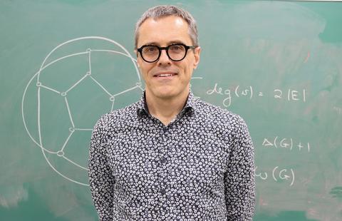 Cobus Swarts stands in front of a chalkboard.